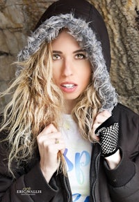 a young woman in a hoodie posing against a rock